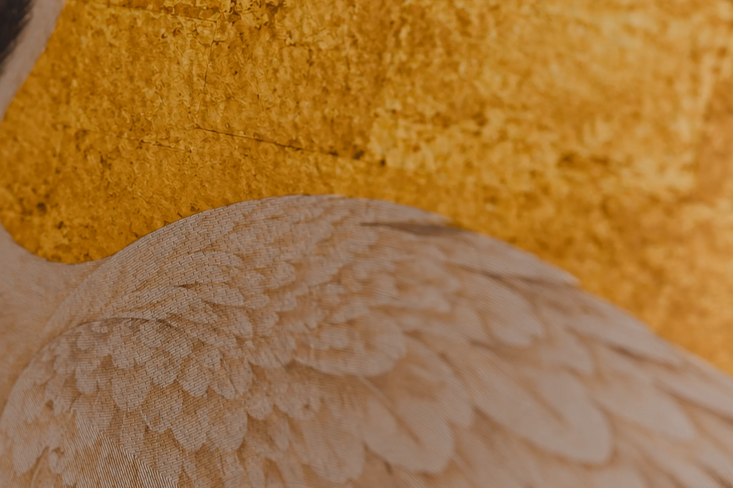 Satin-stitch embroidery of crane feathers on a gold-leaf velvet cushion